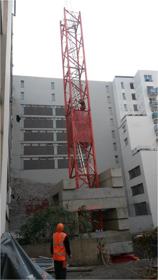 Début de l'installation de la structure verticale de la grue. Les 115 tonnes de lest nécessaires sont passées par-dessus le foyer.